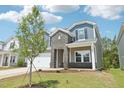 Two-story home with blue and gray siding, brick accents, two-car garage, and a young tree in the front yard at 2211 Cherry Creek Rd, Haw River, NC 27258
