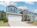 Two-story home featuring gray and blue siding, brick accents, a two-car garage, and a paved driveway at 2211 Cherry Creek Rd, Haw River, NC 27258