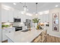 Modern kitchen featuring white cabinets, stainless steel appliances, a large island, and pendant lighting at 293 Providence Creek Dr, Fuquay Varina, NC 27526