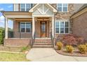 Inviting front porch with brick columns, detailed trim, and a wooden front door at 2936 Turning Brook Ln, Raleigh, NC 27616