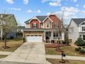 Inviting two-story home with a stone facade, a front porch, and a neatly landscaped front yard at 3914 Glorybower Way, Apex, NC 27502