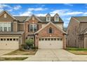 Inviting townhome showcasing brick accents, a two-car garage, and manicured landscaping under a clear blue sky at 520 Brier Crossings Loop, Durham, NC 27703