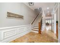 Hallway with hardwood floors and wainscoting, leading to a dining area and stairs with wooden banister at 8418 Wheatstone Ln, Raleigh, NC 27613