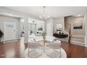 Bright dining area with a modern chandelier, seating for four, and an open floor plan leading to the living room at 912 Ambergate Sta, Apex, NC 27502