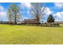 Beautiful farmhouse with a horse grazing on lush green pasture enclosed by a dark wooden fence showcasing idyllic country living at 97 Bailey Rd, Coats, NC 27521