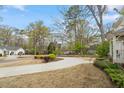 Long, curved driveway approaching a traditional home surrounded by mature trees at 104 Perth Ct, Cary, NC 27511