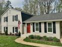 Beautiful home showcasing a red front door, black shutters, and lush green lawn at 1100 Medlin Dr, Cary, NC 27511