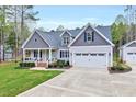 A charming home with a well-manicured lawn, a two-car garage, and an inviting front porch at 1165 Shonele Ln, Stem, NC 27581