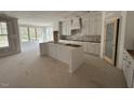 Bright kitchen with large windows, white cabinets, an island, and door to the pantry at 125 Summerlin Dr, Clayton, NC 27527