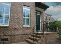 Close up view of brick townhome with a dark green door, brick steps and shutters, and a small black awning at 1523 Yarborough Park Drive, Raleigh, NC 27604