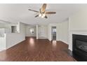 Open living room features hardwood floors, a ceiling fan, and a cozy fireplace at 1905 Maple Sugar Ln, Fuquay Varina, NC 27526