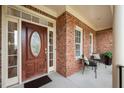 Inviting covered front porch featuring brick columns, a wooden door, and comfortable seating at 21 W Paige Wynd Dr, Angier, NC 27501