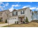 Charming two-story home with gray siding, stone accents, and a two-car garage at 211 Azalea Gaze Dr, Youngsville, NC 27596
