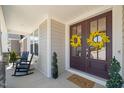 Inviting front porch with rocking chairs and double doors adorned with cheerful yellow wreaths at 216 Ocean Jasper Dr, Holly Springs, NC 27540
