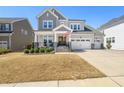 Attractive two-story home featuring a charming front porch, well-maintained lawn, and three-car garage at 216 Ocean Jasper Dr, Holly Springs, NC 27540