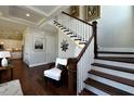 Elegant foyer with hardwood floors, a staircase with white railing, and a stylish seating area showcasing the home's charm at 263 Gilliland Rd, Siler City, NC 27344
