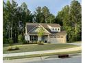 A well manicured yard features a beautiful house with stone accents and 2-car garage at 53 Azul Dr, Clayton, NC 27520