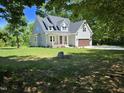 Charming two-story home with a covered front porch, lush green lawn, and attached two-car garage at 5480 Thom Rd, Mebane, NC 27302