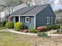 Home exterior with blue siding, white trim, an American flag, and lush landscaping at 7429 Ashbury Ct, Raleigh, NC 27615