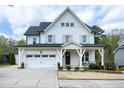 Inviting two-story home featuring a cozy front porch with comfortable seating at 853 Rambling Oaks Ln, Holly Springs, NC 27540