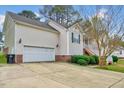Side view of home featuring a two-car garage, brick foundation, landscaped bushes, and a concrete driveway at 91 Buckingham Ct, Smithfield, NC 27577