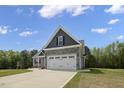 Lovely home featuring a two-car garage, stone details, gray siding, and a neatly maintained lawn at 106 S Harper Faith Way, Benson, NC 27504