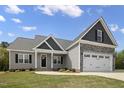 Beautifully designed home with a two-car garage, stone accents, gray siding, and a well-kept lawn at 106 S Harper Faith Way, Benson, NC 27504