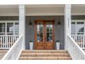 Inviting entryway with double wooden doors, brick steps, and classic white columns at 1221 Azalea Garden Cir, Raleigh, NC 27603