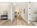 Bright hallway featuring light wood floors and a glimpse of the living room with fireplace at 1221 Azalea Garden Cir, Raleigh, NC 27603
