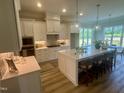 Bright kitchen features white cabinets, a large island with bar seating, and stainless steel appliances at 1221 Azalea Garden Cir, Raleigh, NC 27603
