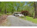 Charming home featuring light gray siding, a welcoming front porch, and a gravel driveway surrounded by lush greenery at 1332 Stallings Rd, Chapel Hill, NC 27516
