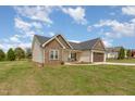 Single-story home with beige siding and a stone facade, a well maintained lawn, and an attached garage at 158 Blande Dr, Kenly, NC 27542