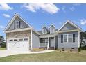 Attractive home exterior with blue siding, stone veneer, dormer windows and a two-car garage at 163 S Harper Faith Way, Benson, NC 27504