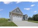 Exterior showing the two-car garage with stone accents, and a paved driveway at 163 S Harper Faith Way, Benson, NC 27504