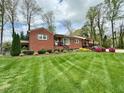 Manicured front yard with a lush green lawn and charming brick home nestled among mature trees at 1802 Greenbriar Rd, Henderson, NC 27536