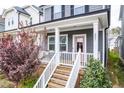 Inviting front porch with white railings, stairs, and a cute pink door, perfect for relaxing at 221 Douglas Falls Dr, Wendell, NC 27591