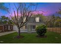 Charming home featuring a well-maintained front yard with mature trees, a picket fence, during a vibrant sunset at 226 1St St, Henderson, NC 27536