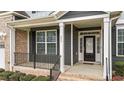 Inviting front porch featuring black railings, brick accents, and a welcoming entrance at 265 Beckwith Ave, Clayton, NC 27527