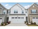 Charming two-story townhouse with a white exterior, attached garage, stone accents, and well-manicured landscaping at 272 Hiking Hill Ln, Garner, NC 27529