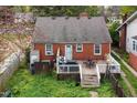 Quaint brick home with a wooden deck, green lawn, and partially fenced yard at 2724 N Roxboro St, Durham, NC 27704