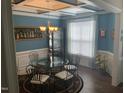 Elegant dining room with a glass table, coffered ceiling, designer chandelier, and large window at 338 Apalachia Lake Dr, Fuquay Varina, NC 27526