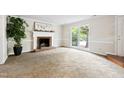 Spacious living room with a brick fireplace, large window, and a classic neutral color scheme at 3421 E Jameson Rd, Raleigh, NC 27604