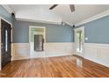 Open-concept living room boasts hardwood floors, wainscoting, and access to the kitchen and back porch at 408 Teal Lake Dr, Holly Springs, NC 27540