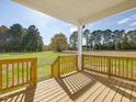 Inviting covered porch with wooden railings offers scenic views of the landscaped backyard at 426 Adams Pointe Ct, Angier, NC 27501