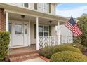 Welcoming front porch with classic columns, American flag, and lush landscaping, enhancing the home's appeal at 43 Summerseat Way, Bunnlevel, NC 28323