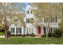 Beautiful two-story home with lush lawn, red door entry, and traditional shutters is framed by mature trees at 4313 Branchwood Dr, Durham, NC 27705