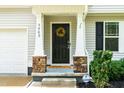 Close-up of a home's front door with decorative wreath, sidelights, and stone accents on porch columns at 5989 Zacks Mill Rd, Angier, NC 27501
