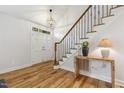 Bright foyer featuring hardwood floors, staircase with iron spindles and a decorative light fixture at 8008 Hollander Pl, Raleigh, NC 27606