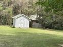 White wooden shed with double doors in a grassy backyard with trees at 103 Kiowa Cv, Louisburg, NC 27549
