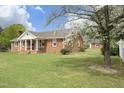 Charming brick home boasts a covered front porch and lush green lawn with mature trees at 1104 W Cole St, Dunn, NC 28334
